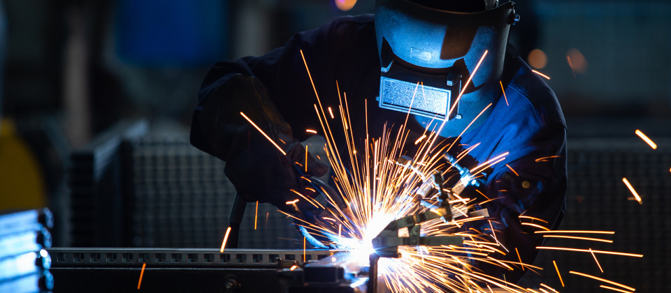 Workers Wearing Industrial Uniforms And Welded Iron Mask At Stee